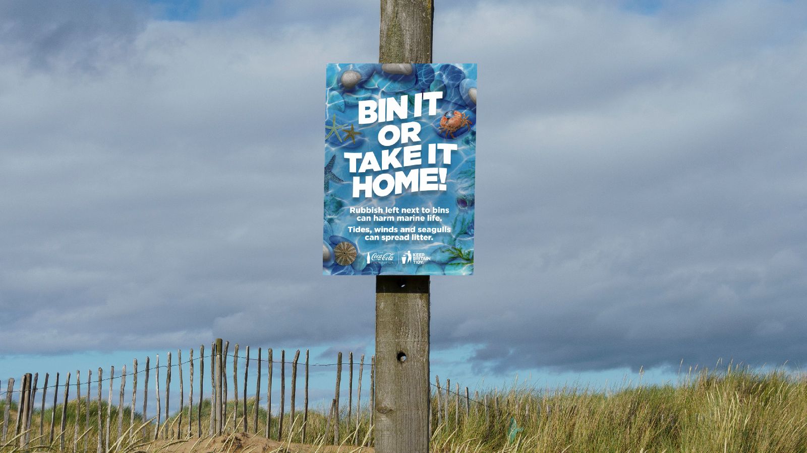 A marine scene with the words 'Bin it or take it home' on it stuck on a lamppost sign.