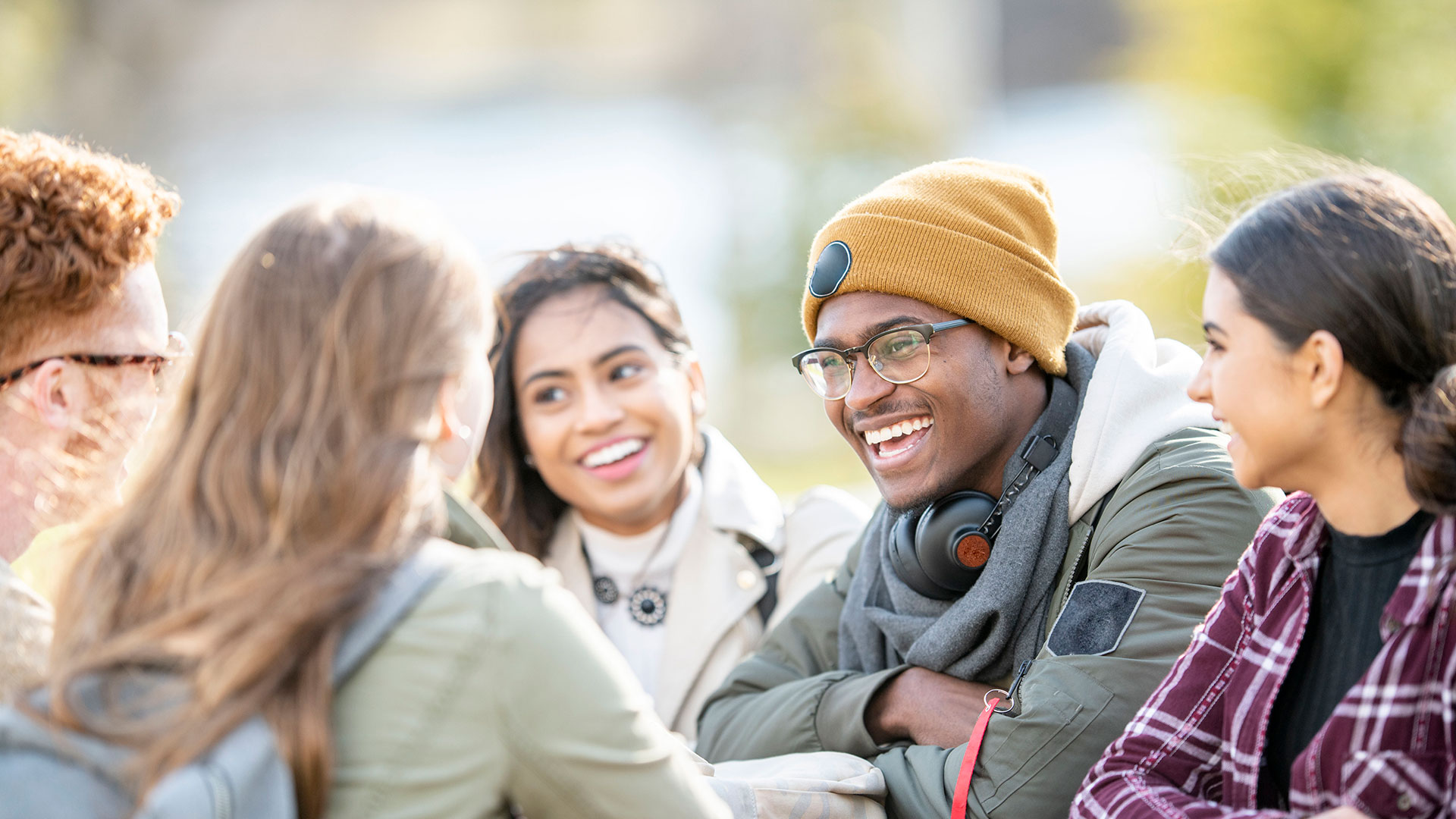Young people sat outside smiling and chatting.